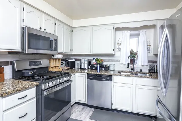 a kitchen with stainless steel appliances granite countertop a stove a sink dishwasher and a refrigerator