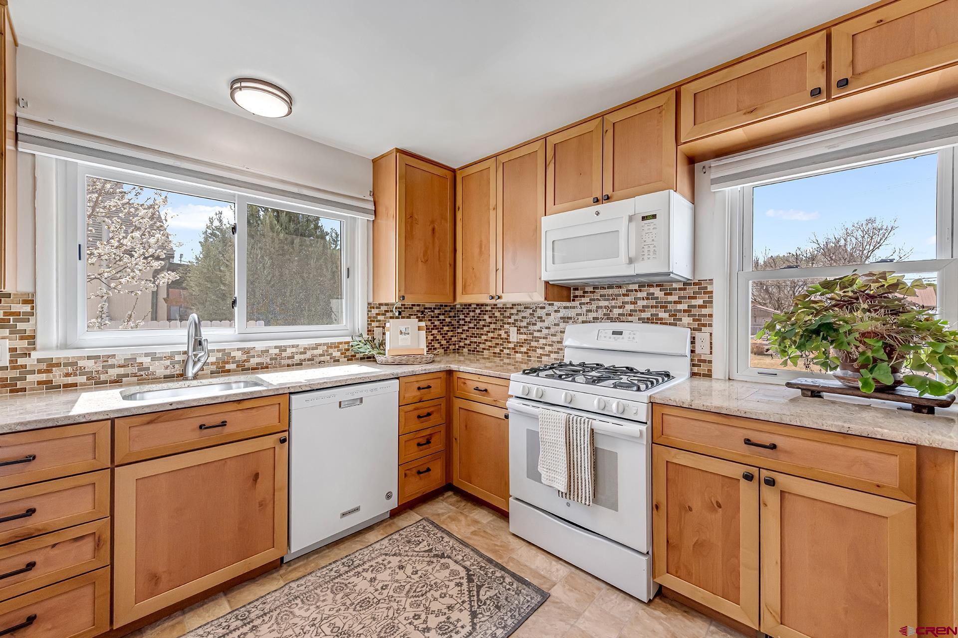 735 Howard Street Delta, CO 81416 - Photo 13 of 34 a kitchen with granite countertop cabinets stainless steel appliances a sink and a large window