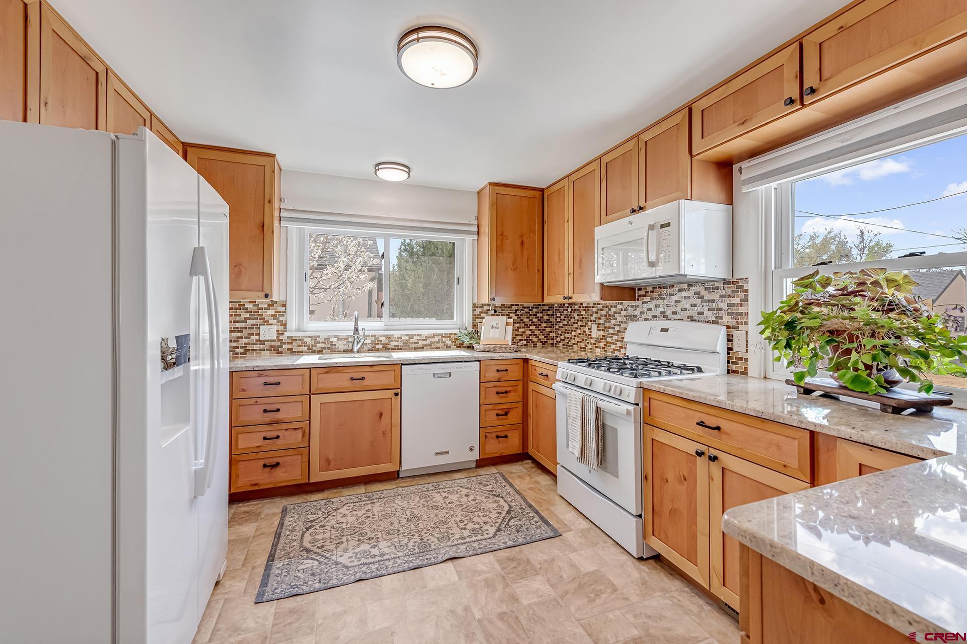 735 Howard Street Delta, CO 81416 - Photo 16 of 34 a kitchen with granite countertop a stove a sink and a refrigerator