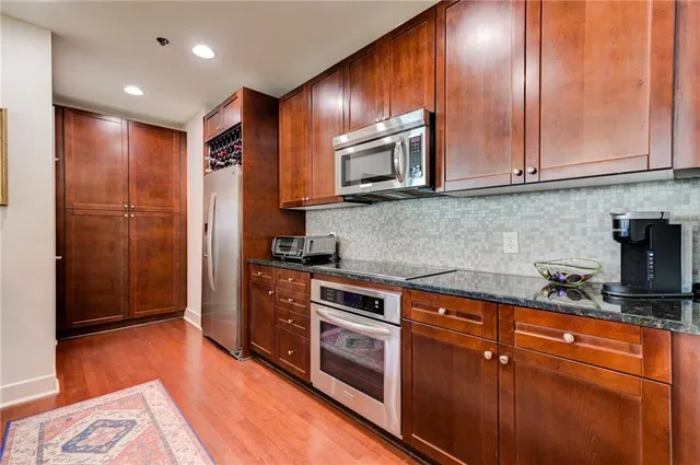 a kitchen with stainless steel appliances granite countertop a stove a sink and a microwave