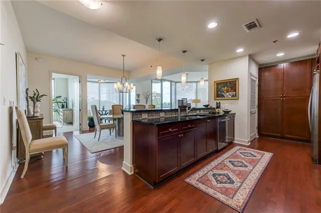 a kitchen with stainless steel appliances granite countertop a refrigerator a sink dishwasher a dining table and chairs with wooden floor