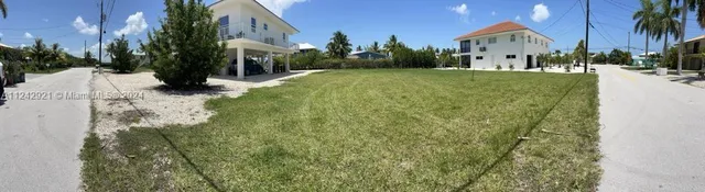 a view of a white house with a yard and potted plants