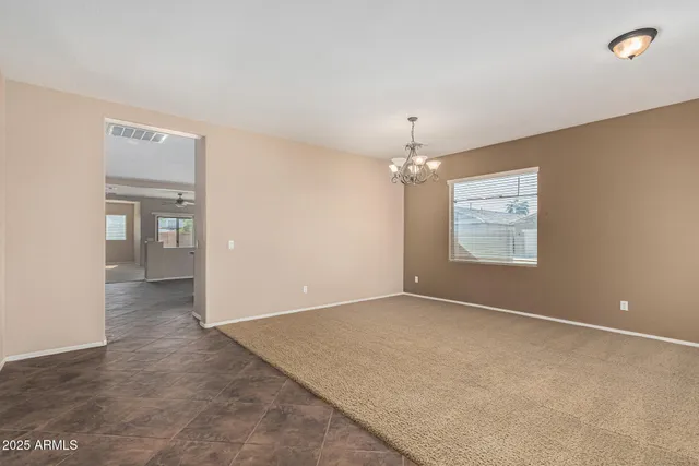 an empty room with a chandelier fan and windows