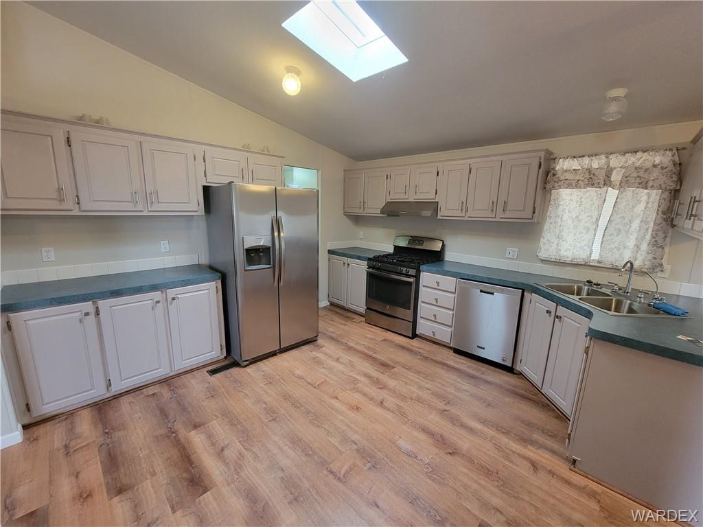 3469 Bouse Road Golden Valley, AZ 86413 - Photo 17 of 37 a kitchen with stainless steel appliances granite countertop a refrigerator a sink dishwasher a stove top oven a refrigerator and white cabinets with wooden floor