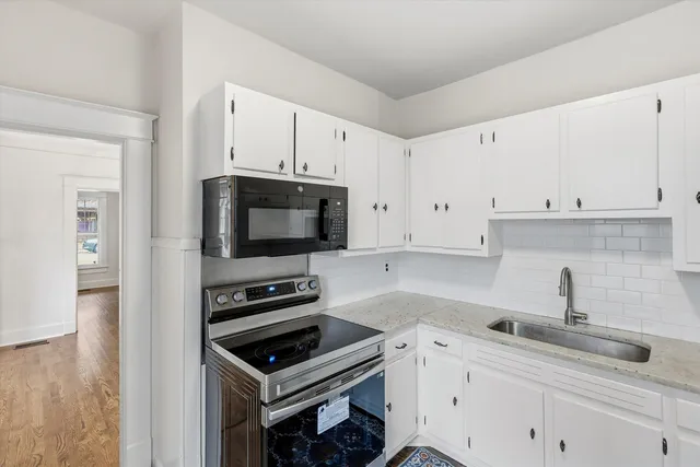 a kitchen with white cabinets a sink and appliances