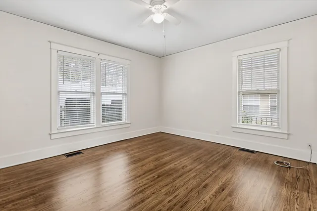 a view of an empty room with wooden floor and a window