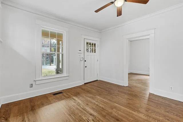 a view of empty room with wooden floor and fan