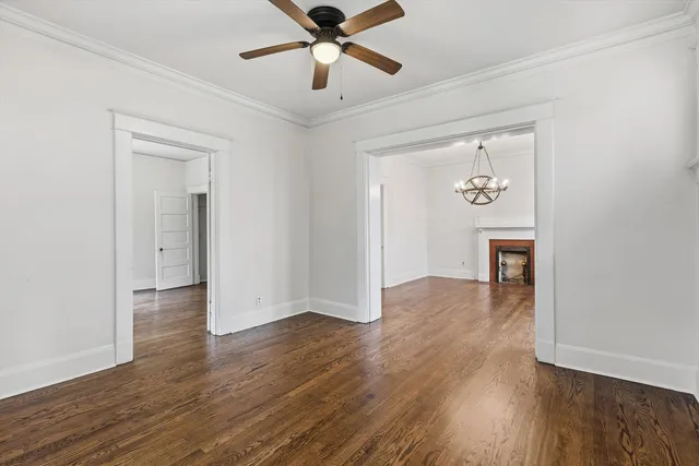 an empty room with wooden floor and ceiling fan