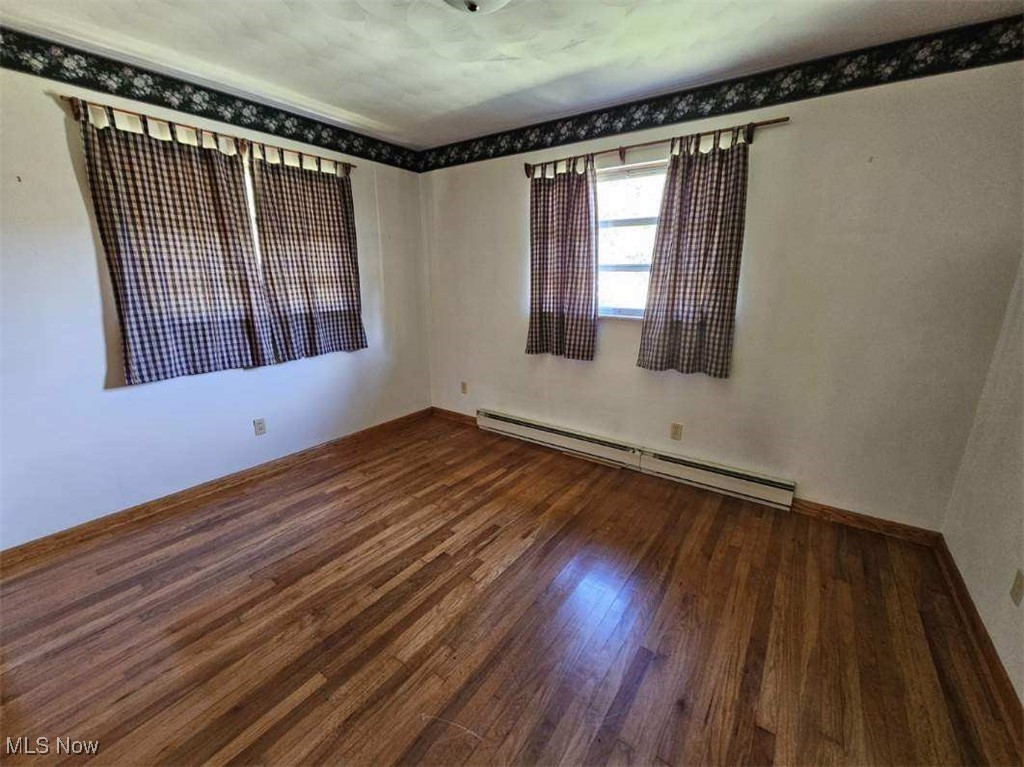 8125 Scio Road Scio, OH 43988 - Photo 7 of 16 Spare room with a baseboard heating unit and dark wood-style flooring