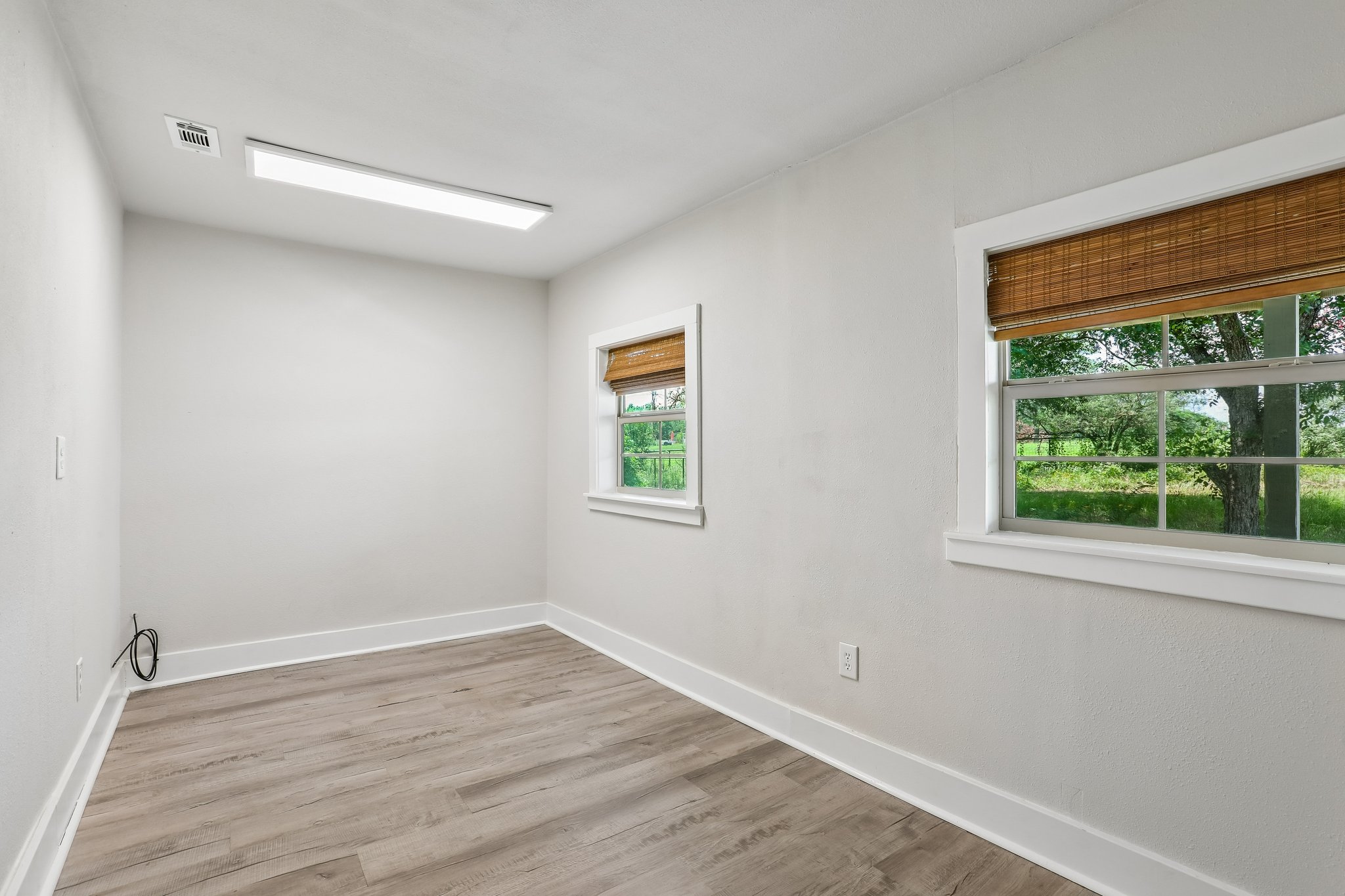 2089 Farm To Market Road 1704 Elgin, TX 78621 - Photo 11 of 31 Well-lit room with wood-look flooring and multiple windows framing green outdoor vistas.