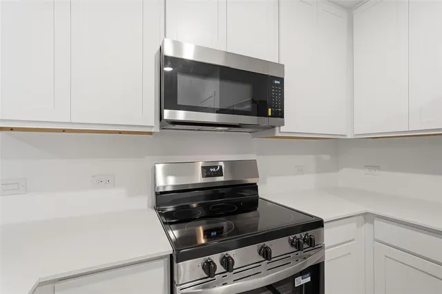 a kitchen with stainless steel appliances a refrigerator a sink a stove a microwave and white counter tops