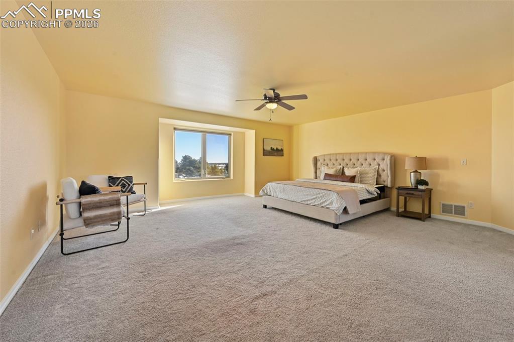 19610 Rathbone Circle Monument, CO 80132 - Photo 19 of 41 a spacious bedroom with a bed and a chandelier