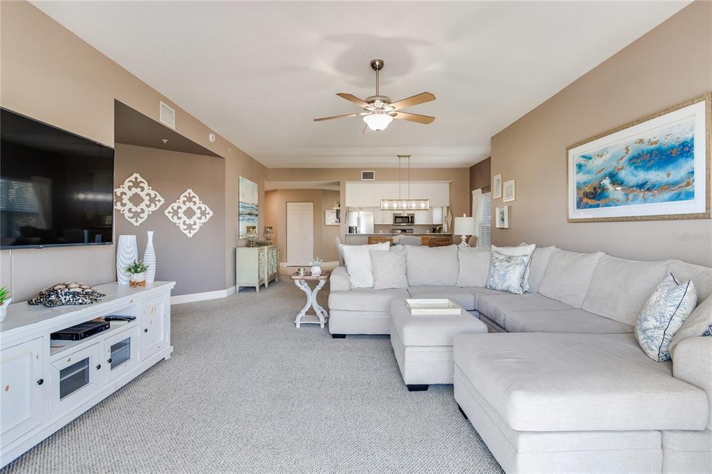 425 150th Avenue, Unit 2301 Madeira Beach, FL 33708 - Photo 17 of 67 a living room with furniture a flat screen tv and kitchen view