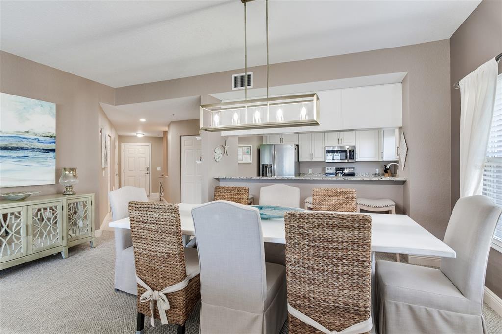425 150th Avenue, Unit 2301 Madeira Beach, FL 33708 - Photo 20 of 67 a kitchen with granite countertop a dining table chairs sink and cabinets