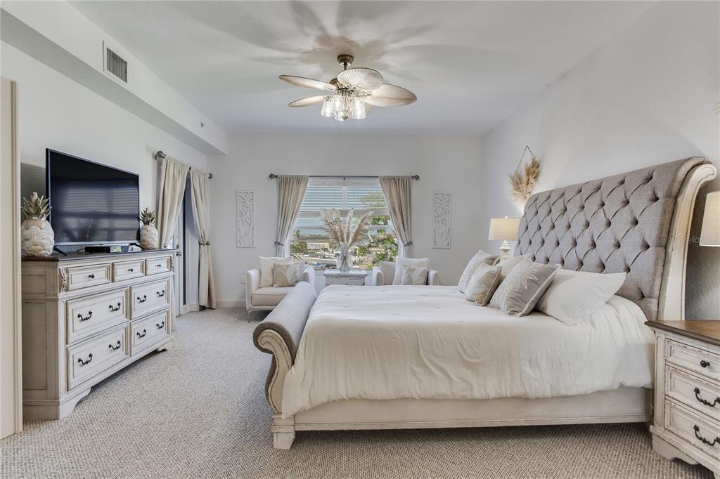 425 150th Avenue, Unit 2301 Madeira Beach, FL 33708 - Photo 28 of 67 a bedroom with a large bed and a flat tv screen on dresser