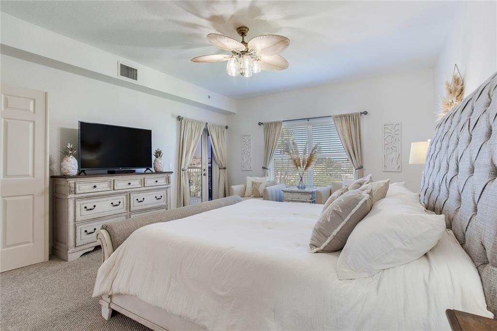 425 150th Avenue, Unit 2301 Madeira Beach, FL 33708 - Photo 29 of 67 a bedroom with a bed flat screen tv and a chandelier