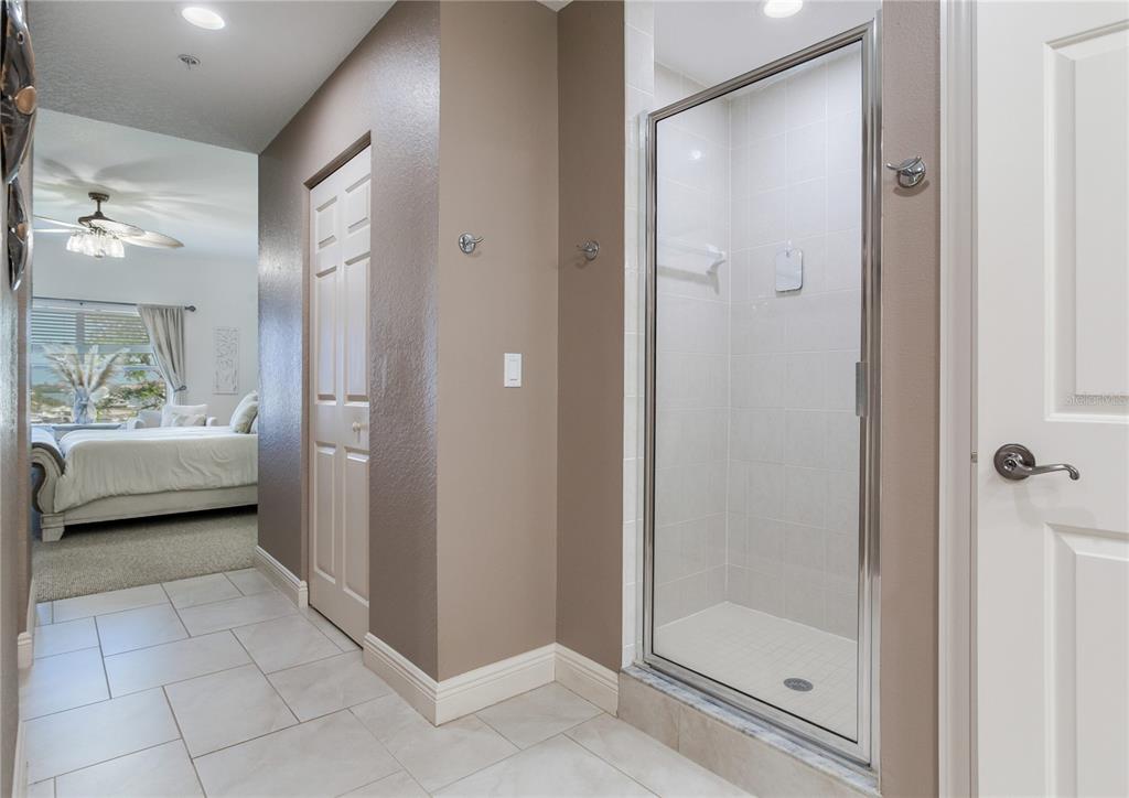 425 150th Avenue, Unit 2301 Madeira Beach, FL 33708 - Photo 35 of 67 a bathroom with a glass shower door a bathtub a sink and a mirror