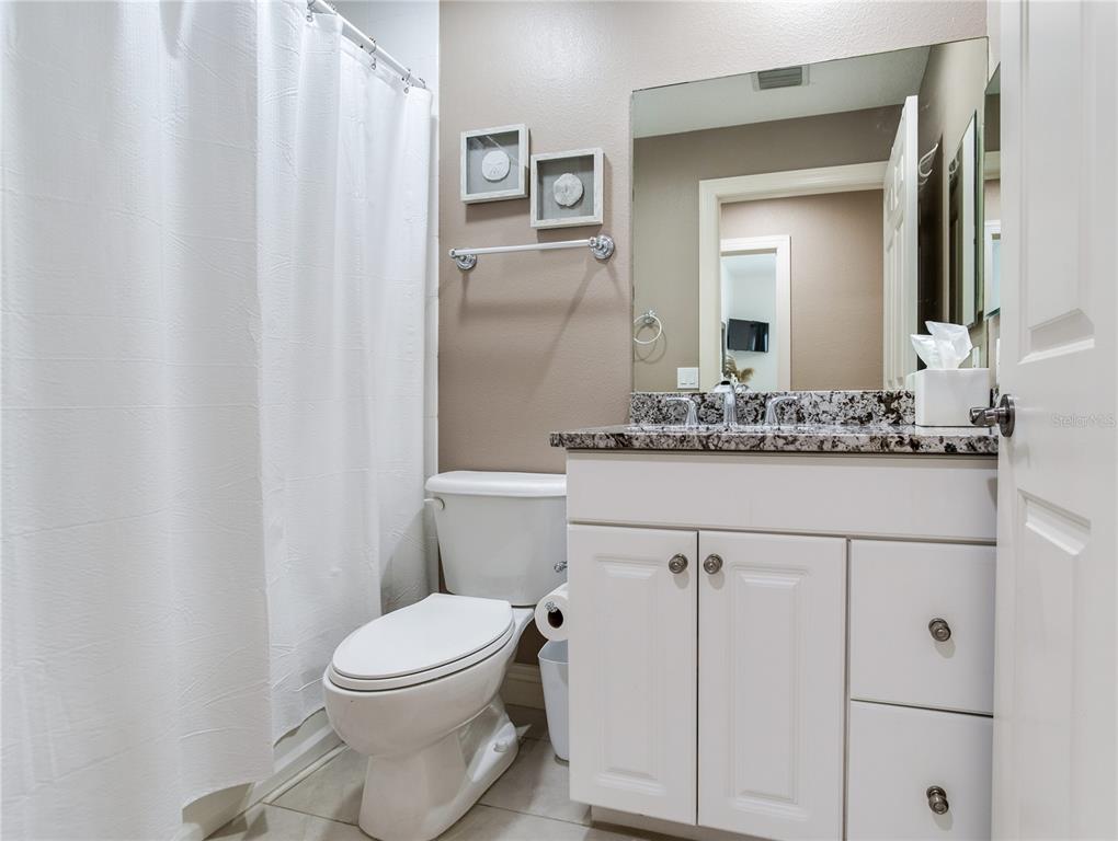 425 150th Avenue, Unit 2301 Madeira Beach, FL 33708 - Photo 38 of 67 a bathroom with a granite countertop toilet sink and mirror