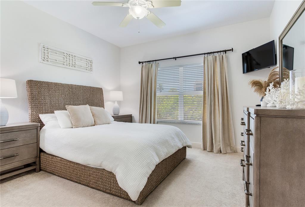 425 150th Avenue, Unit 2301 Madeira Beach, FL 33708 - Photo 39 of 67 a bedroom with a bed and a flat tv screen on dresser