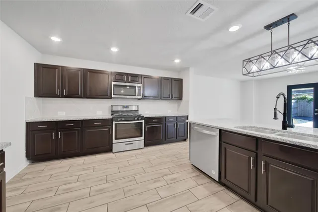 a kitchen with stainless steel appliances granite countertop a sink and stove top oven with wooden floor