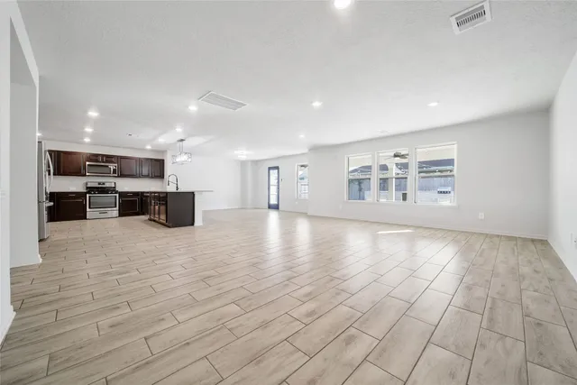 a view of open kitchen with white cabinets and stainless steel appliances