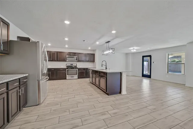 a large kitchen with a large counter top and stainless steel appliances