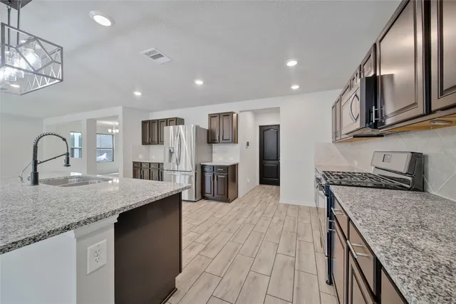 a kitchen with stainless steel appliances granite countertop a sink stove and refrigerator