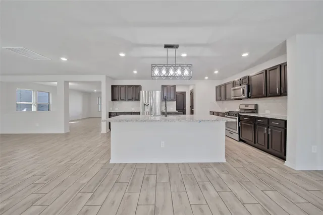 a large kitchen with stainless steel appliances granite countertop a large center island a stove a refrigerator cabinets and living room view