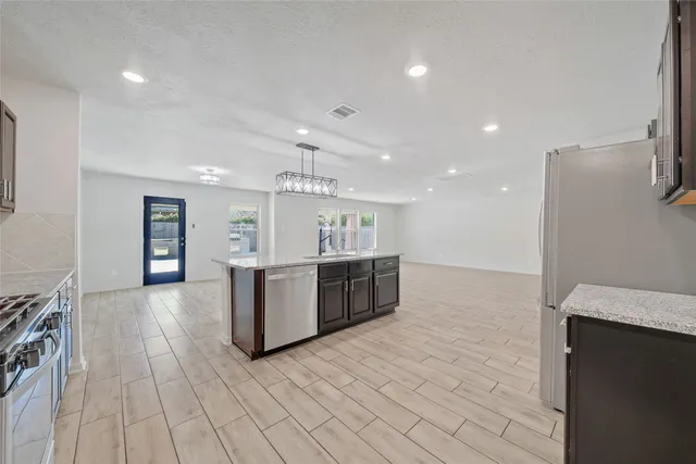a large kitchen with a large counter top and stainless steel appliances