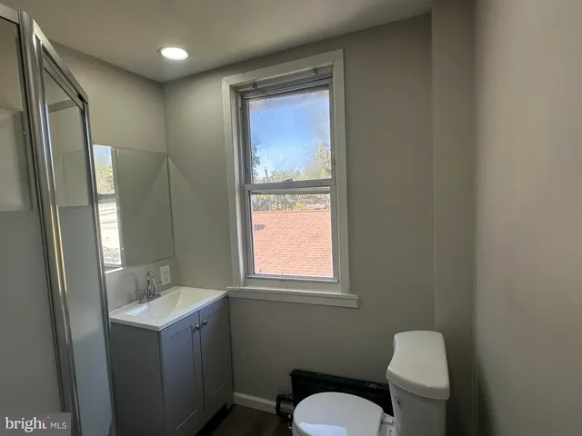 a bathroom with a granite countertop sink toilet and mirror