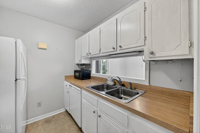 a kitchen with stainless steel appliances granite countertop white cabinets a sink and a white stove