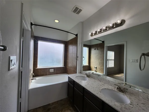 a bathroom with a granite countertop sink mirror and a bathtub