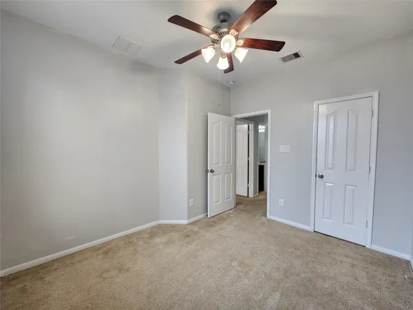 an empty room with a chandelier fan and a ceiling fan