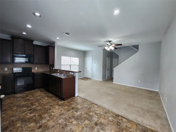 a kitchen with granite countertop a refrigerator stove top oven and cabinets