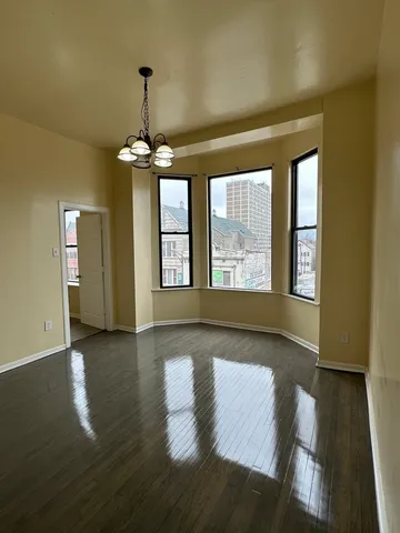 a view of an empty room with window and wooden floor