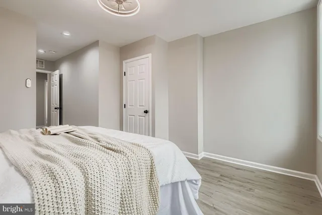 a spacious bedroom with a bed and wooden floor
