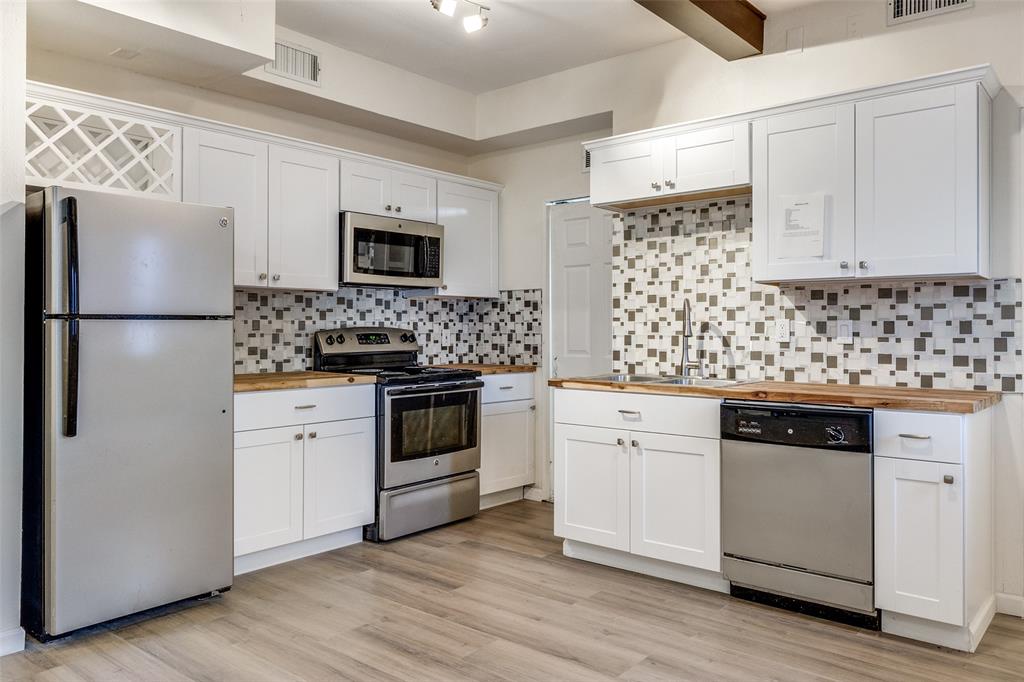 8404 Forest Lane, Unit 702 Dallas, TX 75243 - Photo 6 of 12 a kitchen with white cabinets and stainless steel appliances