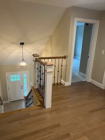 a view of a hallway with wooden floor and stairs