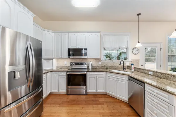 a kitchen with stainless steel appliances granite countertop a sink a stove a refrigerator and a microwave