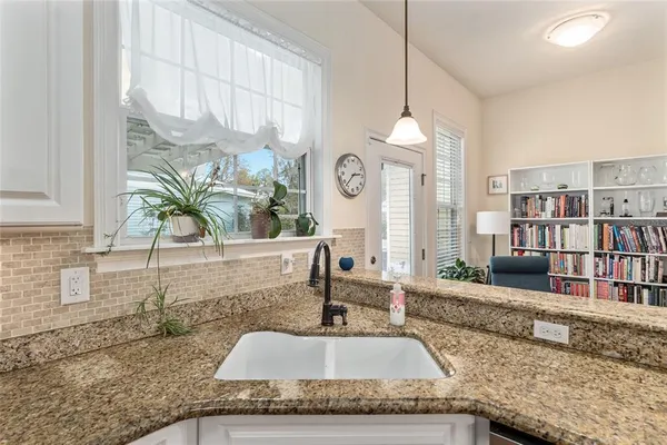 a kitchen with a granite countertop sink a potted plant and a large window