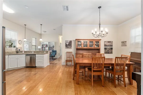 a view of a dining room and livingroom with furniture wooden floor a chandelier