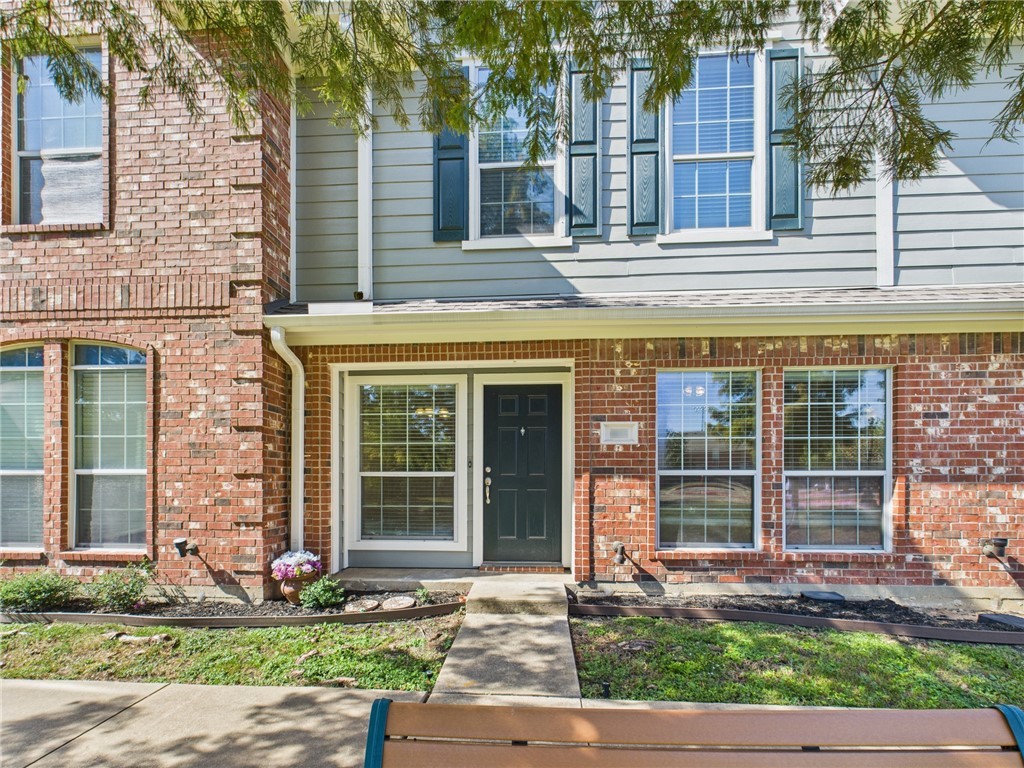 front view of a brick house with a yard and large tree