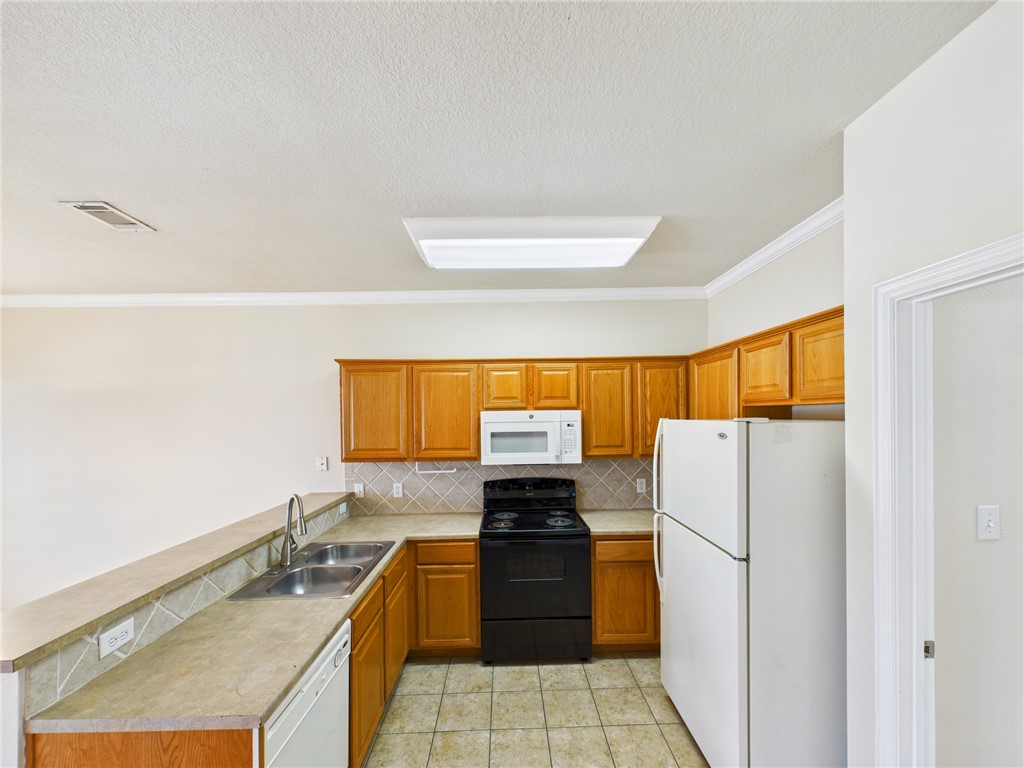 1001 Krenek Tap Road, Unit 603 College Station, TX 77840 - Photo 8 of 31 a kitchen with a refrigerator a stove a sink and a microwave