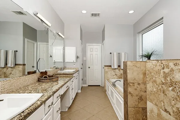 a large bathroom with a granite countertop double vanity sink a mirror and a shower