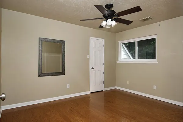 an empty room with wooden floor and ceiling fan