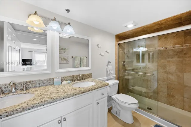 a bathroom with a granite countertop sink a toilet and shower