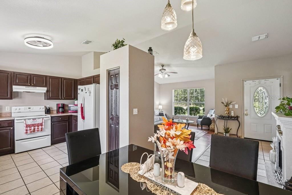 133 Walnut Road Ocala, FL 34480 - Photo 8 of 31 a kitchen with stainless steel appliances a refrigerator a stove a sink dishwasher a dining table and chairs with wooden floor
