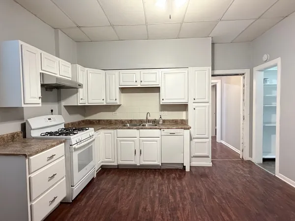 a kitchen with granite countertop white cabinets and white appliances