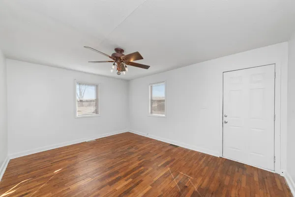 a view of empty room with wooden floor and window