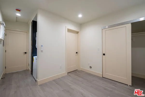 a view of an empty room with wooden floor and closet